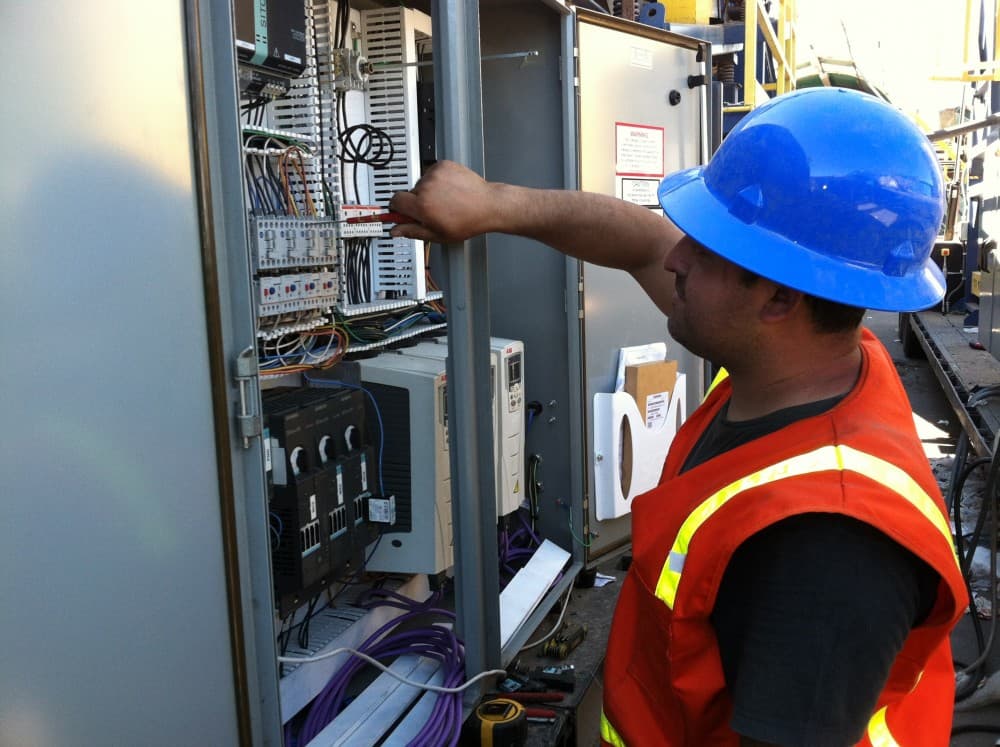 Titus technician wiring an industrial control panel in the field